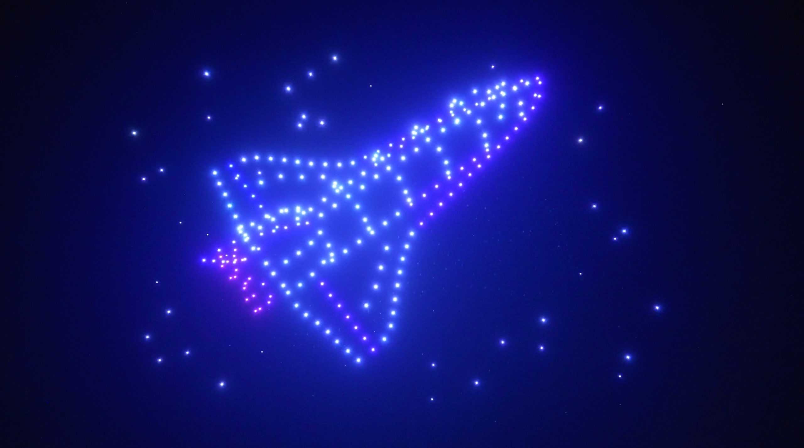 A glowing, multicolored star pattern forming the shape of a spaceship against a dark night sky.